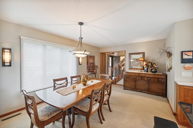 dining room featuring light colored carpet, visible vents, stairway, and baseboards