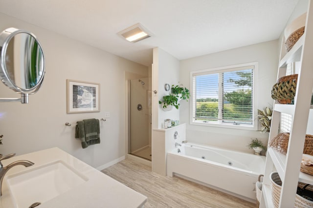 full bath featuring vanity, a shower stall, wood finished floors, a whirlpool tub, and baseboards