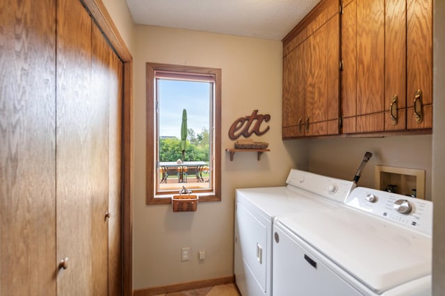 clothes washing area featuring a textured ceiling, separate washer and dryer, cabinet space, and baseboards