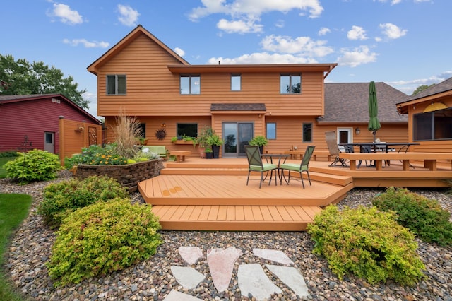 back of property with a deck and outdoor dining area