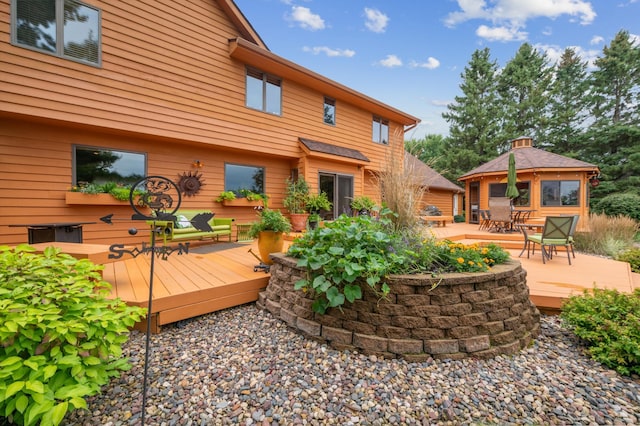 back of property with outdoor dining area, a deck, and a gazebo