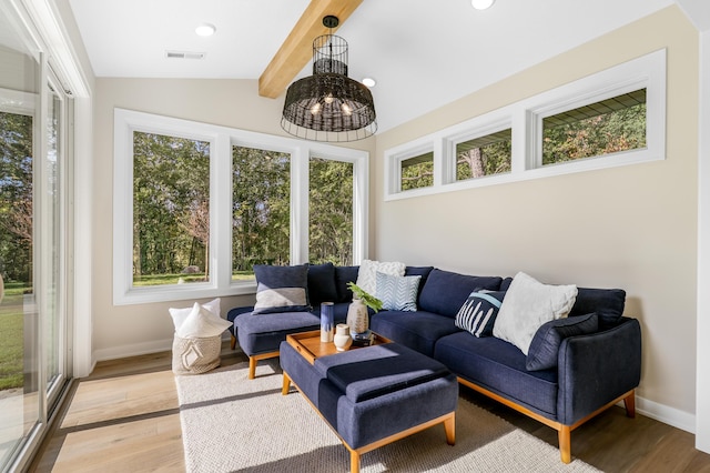 living room featuring an inviting chandelier, lofted ceiling with beams, and light hardwood / wood-style flooring