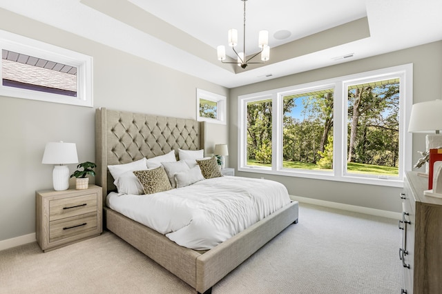 bedroom featuring light carpet, a chandelier, and a tray ceiling