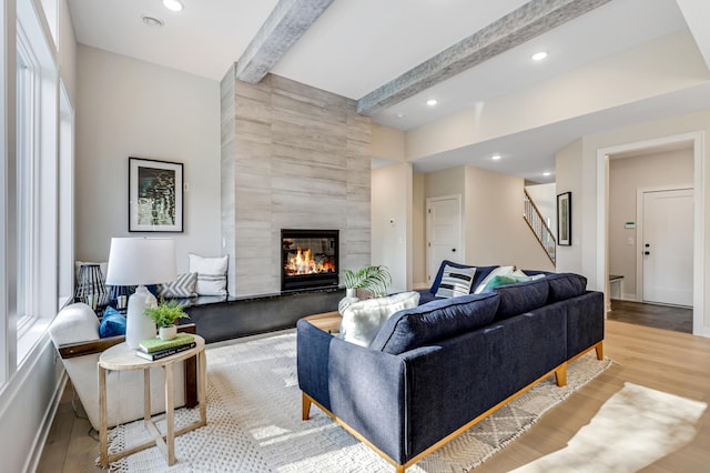 living room with tile walls, light hardwood / wood-style floors, beamed ceiling, and a fireplace