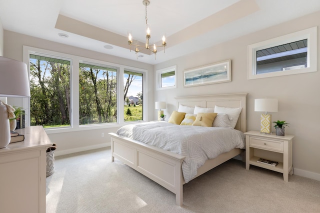 bedroom featuring a chandelier, a raised ceiling, and light carpet