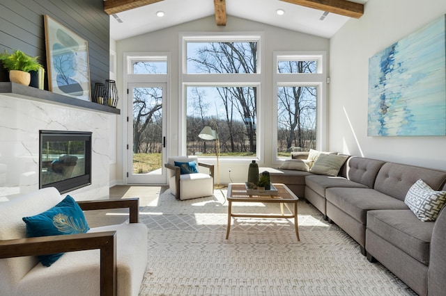 living room featuring a premium fireplace, beamed ceiling, and a healthy amount of sunlight