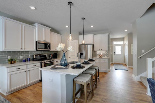 kitchen with white cabinets, appliances with stainless steel finishes, and light hardwood / wood-style floors