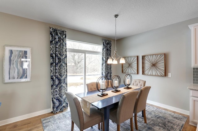 dining space featuring a chandelier, a textured ceiling, and light hardwood / wood-style floors