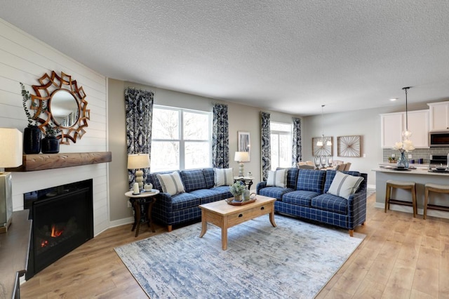 living room with a textured ceiling, a fireplace, and light hardwood / wood-style flooring