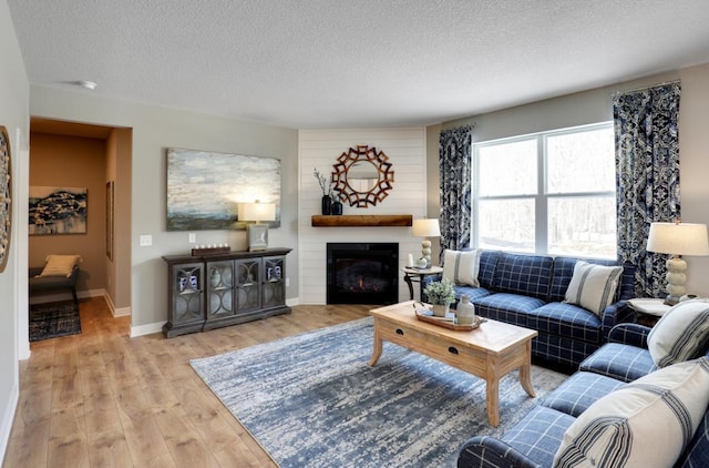 living room featuring a textured ceiling, a fireplace, and light hardwood / wood-style flooring