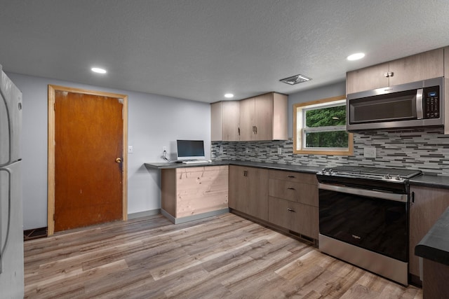 kitchen featuring appliances with stainless steel finishes, light hardwood / wood-style flooring, a textured ceiling, and backsplash