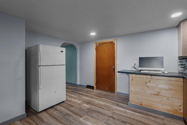 kitchen featuring white fridge, a textured ceiling, and light wood-type flooring