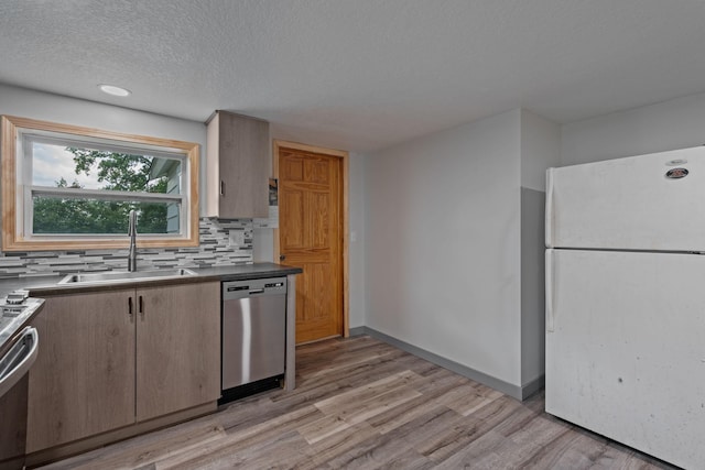 kitchen with tasteful backsplash, stainless steel dishwasher, light hardwood / wood-style flooring, white fridge, and sink