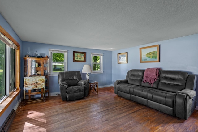 living room featuring dark wood-type flooring, a textured ceiling, and a baseboard radiator