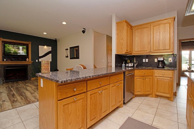 kitchen featuring dishwasher, kitchen peninsula, and dark stone countertops