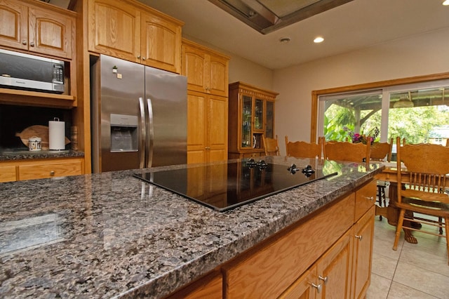 kitchen with light tile patterned flooring, glass insert cabinets, recessed lighting, dark stone counters, and appliances with stainless steel finishes