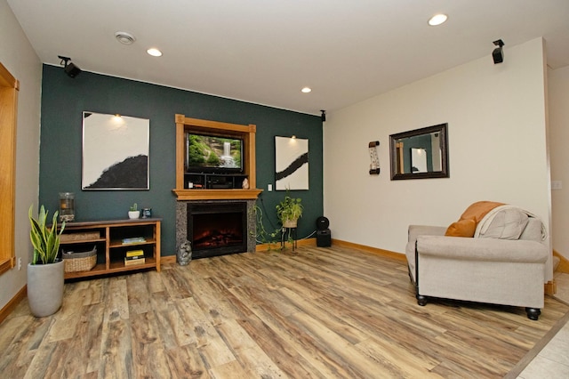 sitting room featuring recessed lighting, baseboards, a lit fireplace, and wood finished floors