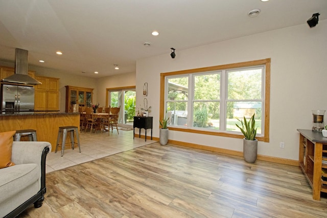 living room with recessed lighting, baseboards, and light wood-type flooring