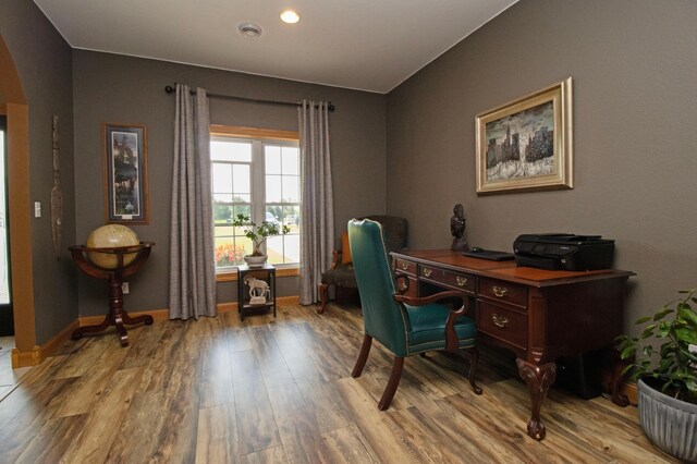 office space featuring baseboards, arched walkways, wood finished floors, and visible vents