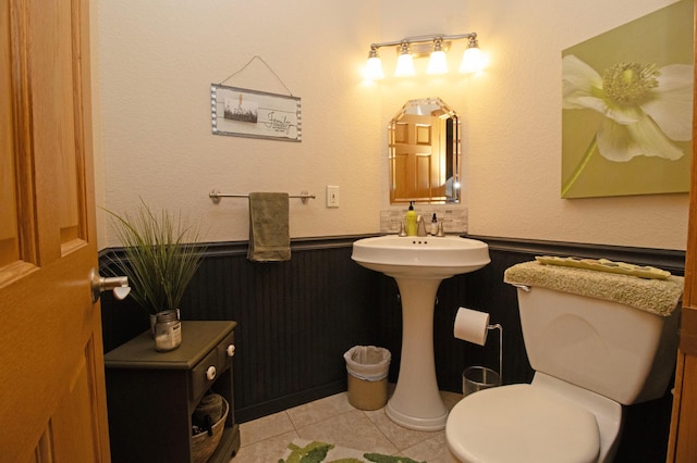 bathroom featuring tile patterned flooring, a wainscoted wall, and toilet