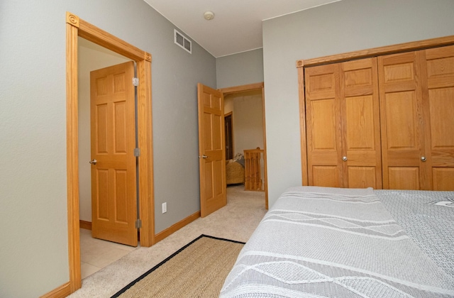 bedroom with visible vents, baseboards, a closet, and light carpet
