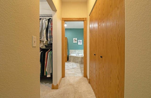 hall with baseboards, carpet flooring, and a textured wall