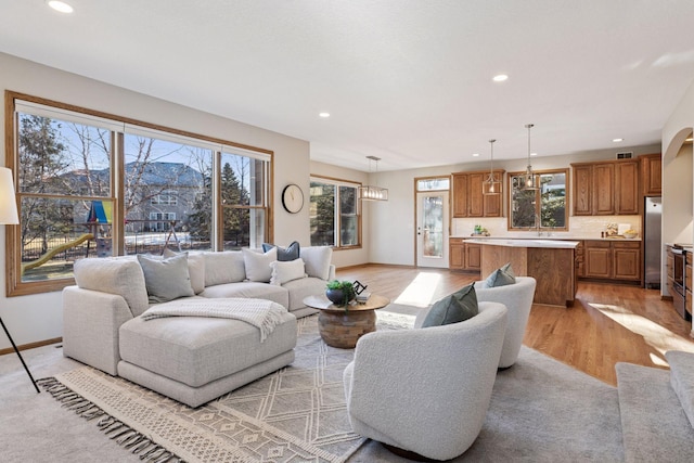 living area featuring light wood finished floors, baseboards, a wealth of natural light, and recessed lighting