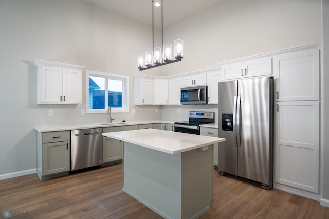 kitchen with decorative light fixtures, appliances with stainless steel finishes, dark hardwood / wood-style flooring, high vaulted ceiling, and a kitchen island