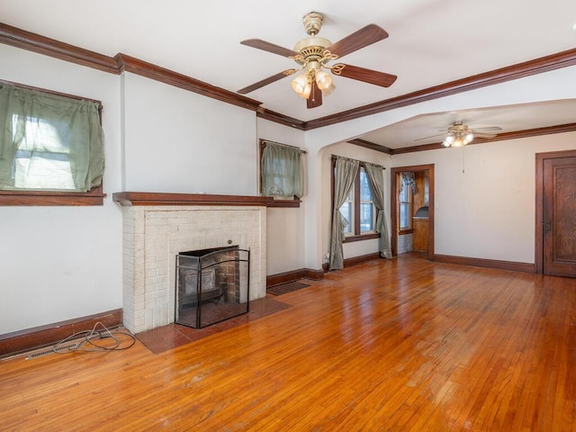 unfurnished living room featuring wood-type flooring, a brick fireplace, ceiling fan, and crown molding