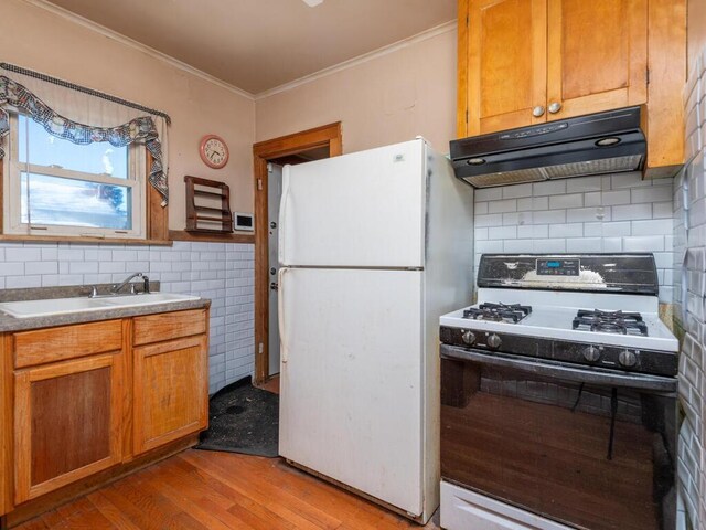 kitchen featuring white appliances, backsplash, crown molding, sink, and light hardwood / wood-style floors