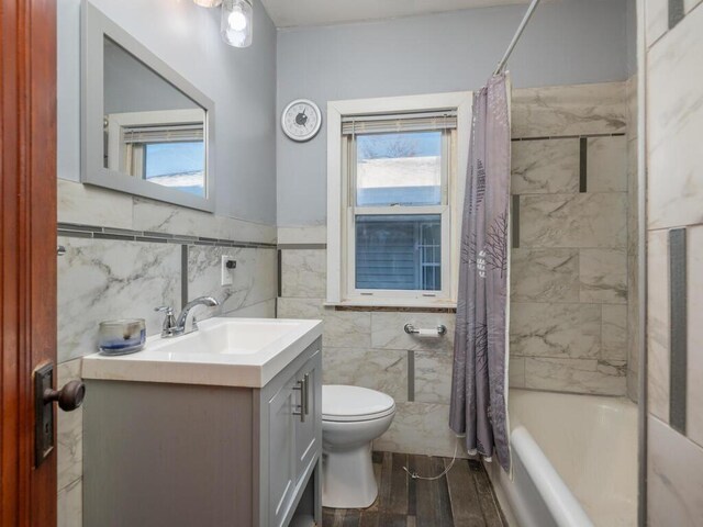 full bathroom featuring shower / bath combo, vanity, wood-type flooring, tile walls, and toilet