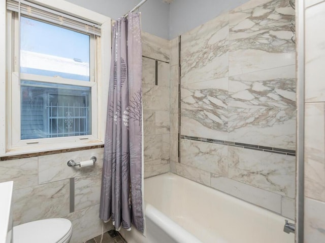 bathroom with shower / bathtub combination with curtain, tile walls, and toilet