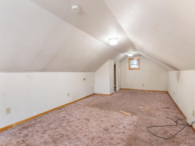 bonus room with light colored carpet and vaulted ceiling