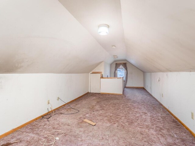 bonus room with light carpet and lofted ceiling