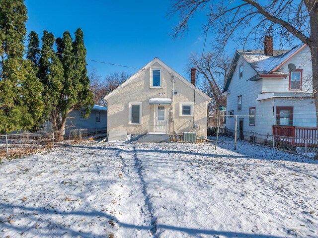 snow covered rear of property with central air condition unit