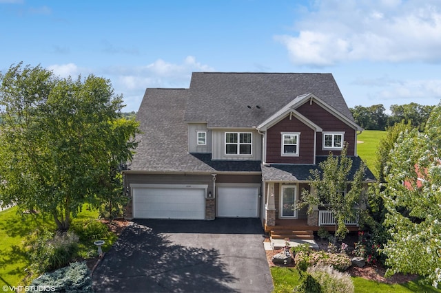 craftsman-style home featuring aphalt driveway, a shingled roof, a porch, board and batten siding, and a garage