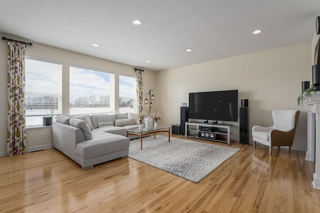 living room with light wood-style flooring, baseboards, a textured ceiling, and recessed lighting