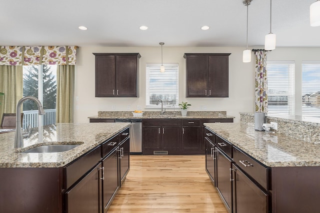 kitchen featuring an island with sink, stainless steel dishwasher, and a sink