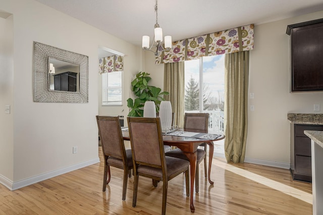 dining room featuring light wood finished floors, an inviting chandelier, and baseboards