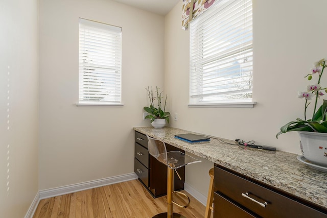 office space with baseboards, built in study area, and light wood finished floors