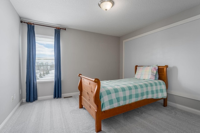 bedroom with a textured ceiling, carpet flooring, visible vents, and baseboards