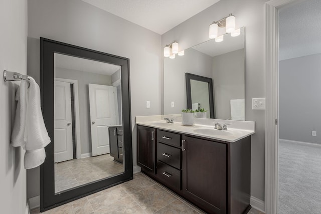 bathroom with double vanity, baseboards, and a sink