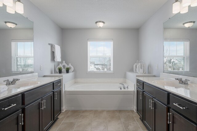 bathroom with two vanities, tile patterned flooring, a sink, and a bath