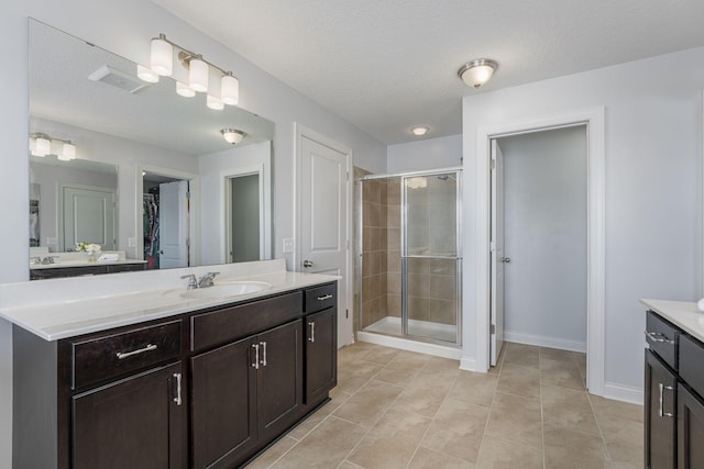 full bathroom with visible vents, a stall shower, a textured ceiling, and vanity