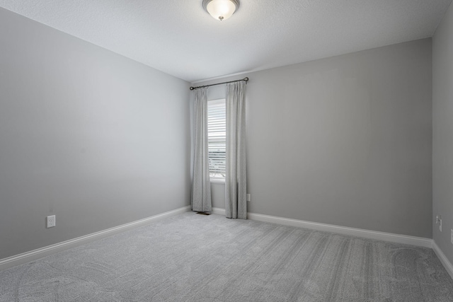 spare room featuring a textured ceiling, carpet floors, and baseboards