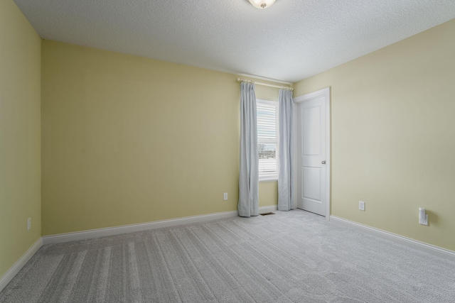 spare room with carpet floors, baseboards, and a textured ceiling