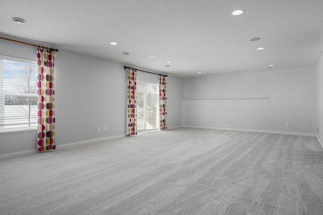 carpeted empty room with a textured ceiling, recessed lighting, and baseboards