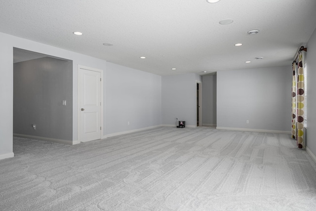 unfurnished room featuring recessed lighting, light carpet, a textured ceiling, and baseboards