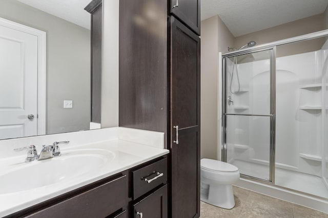 bathroom featuring a textured ceiling, a shower stall, toilet, and vanity