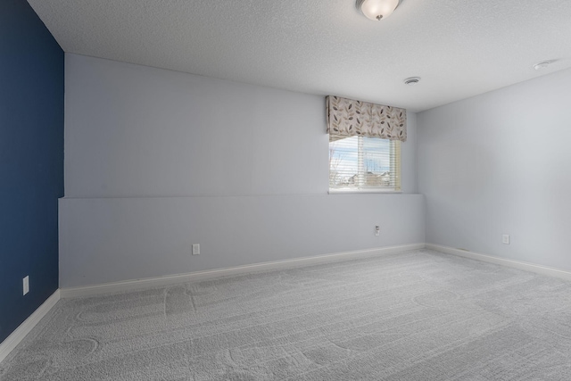 carpeted empty room featuring a textured ceiling and baseboards